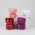 Four colorful teddy bear-shaped containers with flowers on a pink background